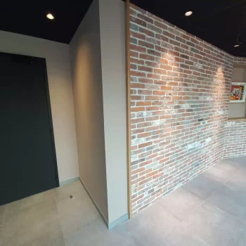 Mur en parement de briques et murs peints gris anthracite dans un local professionnel