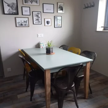 Salle à manger aux murs gris taupe avec cadres photos et chaises métal