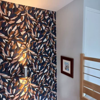 Montée d'escalier avec papier peint à motif feuilles noir et cuivre