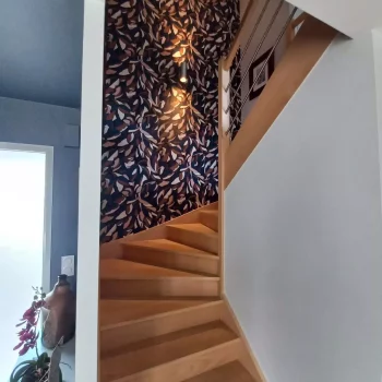 Escalier en bois et mur tapissé d'un papier peint feuillage