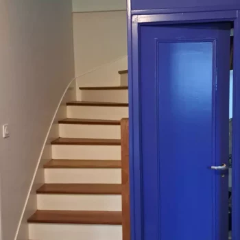 Escalier, porte peinte en bleu intense et sol en damier noir et blanc