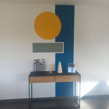 Entrée avec bande bleu canard et cercle jaune moutarde peints sur le mur