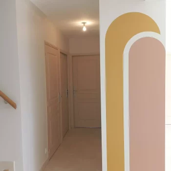 Couloir avec arches peintes en jaune moutarde et rose poudré