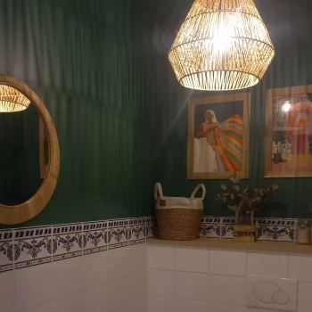 Toilettes peintes en vert foncé avec suspension en rotin et frise de carreaux