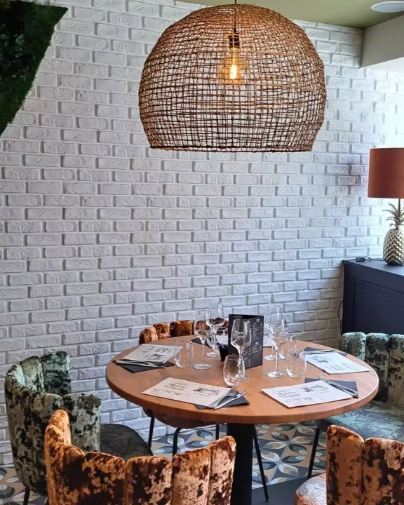 Coin repas avec mur en briques blanches et suspension en rotin