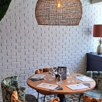 Coin repas avec mur en briques blanches et suspension en rotin