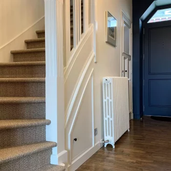 Escalier rénové avec moquette en fibres naturelles, contremarches blanches et porte bleue