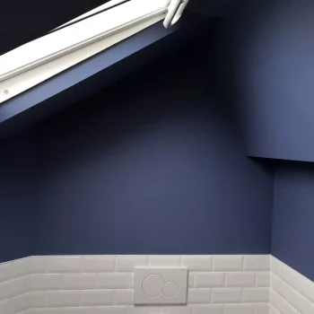 Salle de bain sous combles peinte en bleu nuit avec carrelage métro blanc