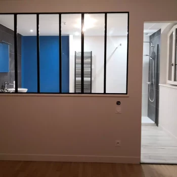 Verrière d'atelier noire entre deux pièces aux murs peints en bleu