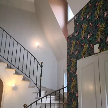 Cage d'escalier avec papier peint jungle et rampe en fer forgé