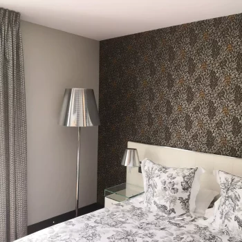 Chambre avec papier peint à motif feuillage doré derrière la tête de lit