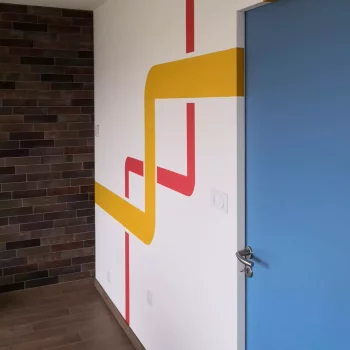 Salon à Saint-Barnabé avec décor mural graphique jaune et rouge et porte bleue